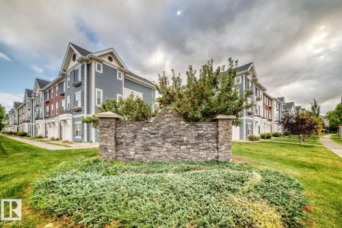 Stone facade with capstone accents, mature plantings, and manicured green spaces - #20 8315 180 Av Nw, Edmonton, AB 