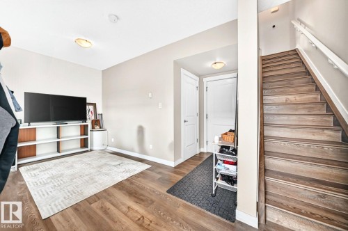 Wood-finish flooring throughout, white interior doors, staircase with wood-finish treads and white railing, and flush-mount ceiling lights - #20 8315 180 Av Nw, Edmonton, AB 