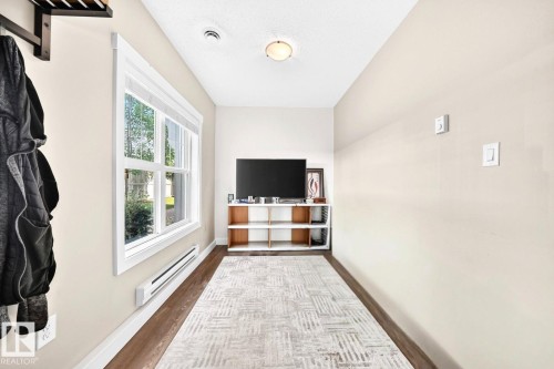 Wood-finish flooring, white trim, and a built-in wall heater complement the window with a white blind - #20 8315 180 Av Nw, Edmonton, AB 