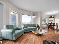 Open-concept living and dining area featuring wood-finish flooring, multiple windows with blinds, and a contemporary chandelier in the dining space - 