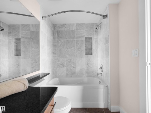 Bathtub with integrated shower, white subway tile surround, recessed shower niche, curved shower rod, and chrome fixtures - #1601 10136 104 St Nw, Edmonton, AB 