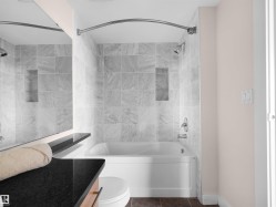 Bathtub with integrated shower, white subway tile surround, recessed shower niche, curved shower rod, and chrome fixtures - 