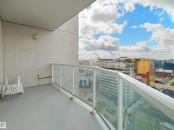 Private balcony with glass railing, urban cityscape, and overhead lighting fixture - 