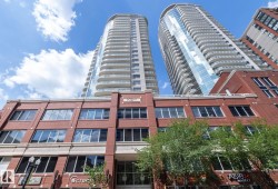 Modern high-rise residential buildings with multiple balconies, a brick facade base, and prominent storefront windows - 