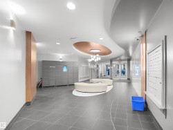 Lobby with gray large format tile flooring, curved white and copper ceiling design, and a modern chandelier - 