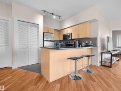 Kitchen featuring a breakfast bar with dark countertop, wood-finish cabinetry, stainless steel appliances, and track lighting - 