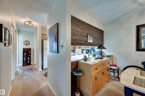 Hardwood flooring extending through the hallway, contemporary flush mount lighting, and a wood plank accent wall - #203 24 Alpine Pl, St. Albert, AB 