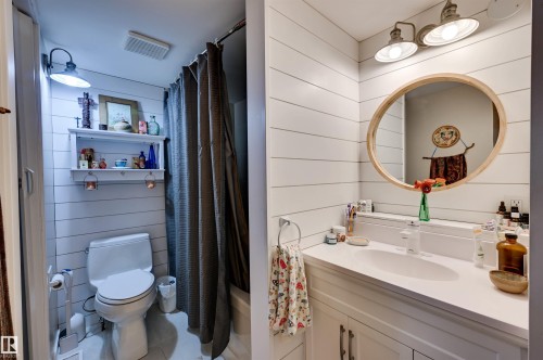 Shiplap wall paneling, built-in shelving, vanity with integrated sink, wood-framed mirror, and industrial-style wall sconces - #203 24 Alpine Pl, St. Albert, AB 