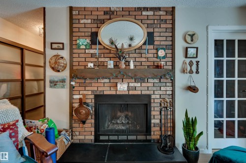 Brick fireplace with a dark mantel, a black hearth, and wood trim - #203 24 Alpine Pl, St. Albert, AB 