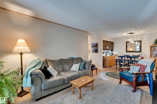 Open-concept living area with light wood-finish flooring, recessed lighting, and a dining space featuring a chandelier - #203 24 Alpine Pl, St. Albert, AB 