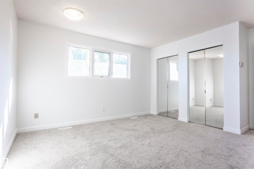 Recessed ceiling light fixture, neutral carpet, white walls, and dual mirrored closet doors - 17927 80 Avenue Nw, Edmonton, AB 