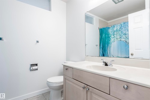Bathroom featuring a single vanity with an integrated sink, polished chrome fixtures, and a large wall-mounted mirror - 17927 80 Avenue Nw, Edmonton, AB 