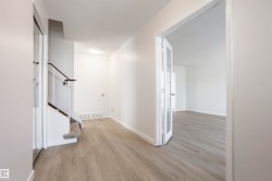 Wood-finish flooring, white walls, flush mount lighting, a staircase with carpeting, and glass-paneled French doors - 
