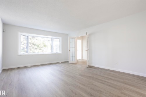 Spacious room featuring wood-finish flooring, white walls, and a large bay window - 17927 80 Avenue Nw, Edmonton, AB 