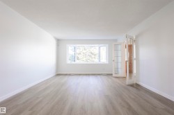 Expansive room featuring wood-finish flooring, white walls, a large bay window, and French doors with glass panels - 