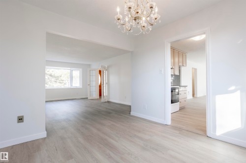Recessed archway, crystal chandelier, wood-finish flooring, white painted walls, and a large window - 17927 80 Avenue Nw, Edmonton, AB 