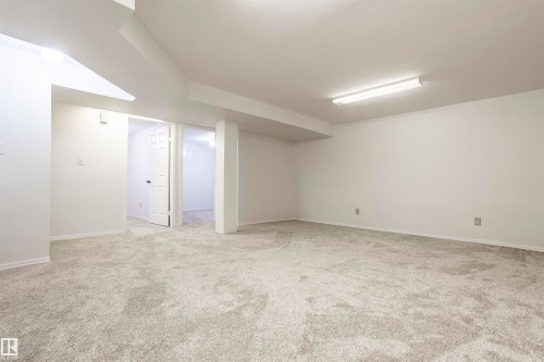 Expansive carpeted room with neutral wall finishes, recessed lighting, and a white interior door - 17927 80 Avenue Nw, Edmonton, AB 