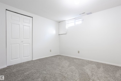 Neutral wall tones with gray carpeting, featuring a bi-fold closet door and a high-set window - 17927 80 Avenue Nw, Edmonton, AB 