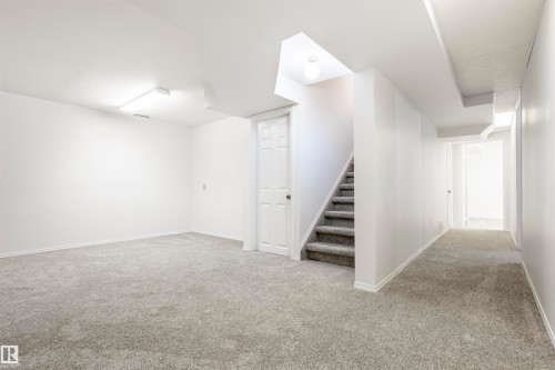 Spacious lower-level room featuring light gray carpeting, white walls, and bright overhead lighting - 17927 80 Avenue Nw, Edmonton, AB 