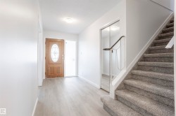 Wood-finish flooring in the entryway with a wood front door featuring an oval decorative glass insert - 
