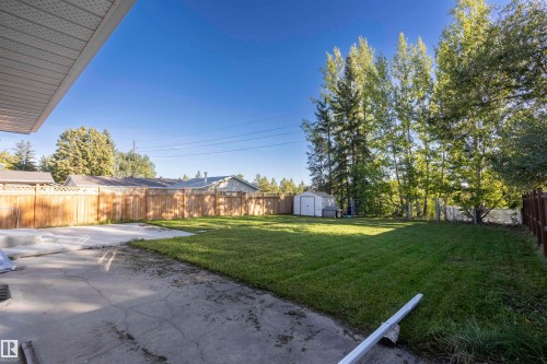 Expansive backyard featuring a manicured lawn, concrete patio, and a storage shed - 17927 80 Avenue Nw, Edmonton, AB 