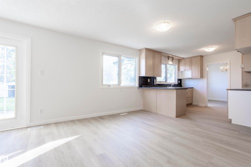 Open-concept layout featuring wood-finish flooring, a kitchen island with dark countertops, and light-toned cabinetry - 17927 80 Avenue Nw, Edmonton, AB 
