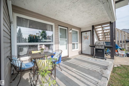 Covered patio with durable concrete flooring, white frame windows, and two entry doors - 15017 26 Street Nw, Edmonton, AB 