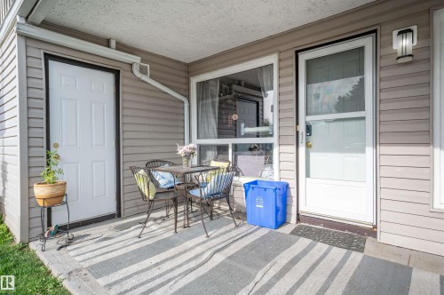 Covered patio with durable concrete flooring, siding exterior, exterior lighting fixture, and white entry door - 15017 26 Street Nw, Edmonton, AB 