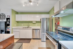 Kitchen featuring white cabinetry, stainless steel appliances, a dual basin sink, and track lighting - 