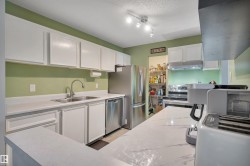 White cabinetry, stainless steel appliances, solid surface countertops, track lighting, and a double basin sink - 