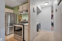 Stainless steel appliance suite, white cabinetry, light-toned flooring, and integrated laundry appliances - 