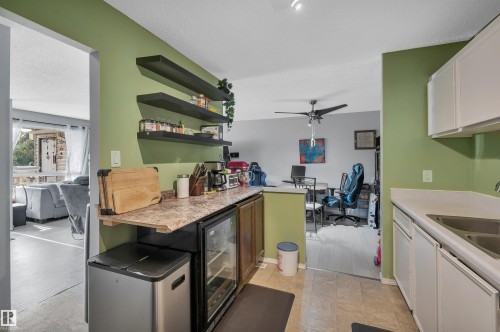Kitchen featuring white cabinetry, light countertops, and a stainless steel sink - 15017 26 Street Nw, Edmonton, AB 