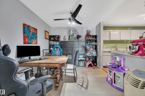 Open-concept layout with light wood-finish flooring, a ceiling fan, and built-in shelving - 15017 26 Street Nw, Edmonton, AB 