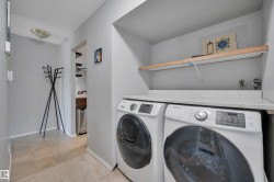 Dedicated laundry area featuring a countertop surface, overhead shelving, and neutral wall tones - 