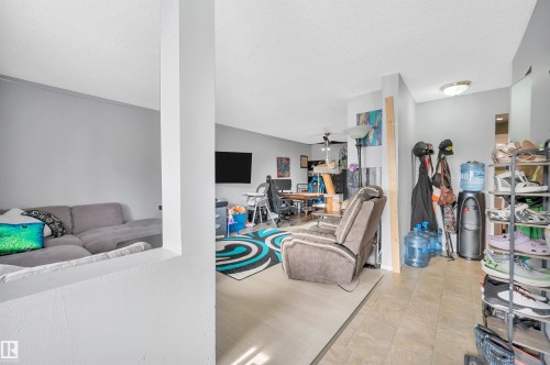 Open-concept living space featuring light-toned walls, recessed lighting, and a combination of wood-finish and tiled flooring - 15017 26 Street Nw, Edmonton, AB 