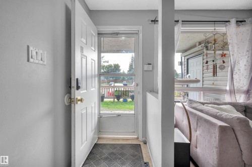 Entryway featuring a panel door with brass hardware and a screen door - 15017 26 Street Nw, Edmonton, AB 
