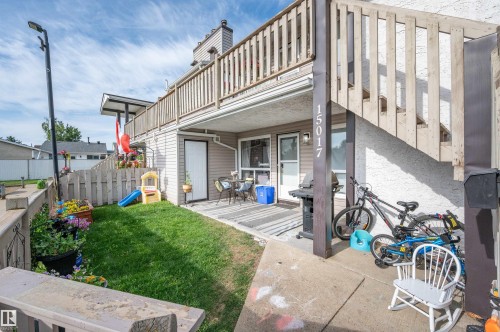 Ground-level patio with direct lawn access, wood privacy fencing, and exterior wall siding - 15017 26 Street Nw, Edmonton, AB 