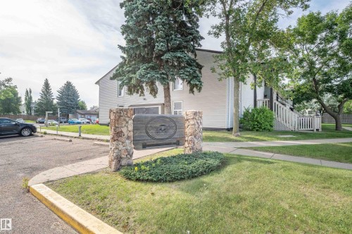 Wood-sided multi-level building with exterior stairs and a stone-clad sign - 15017 26 Street Nw, Edmonton, AB 