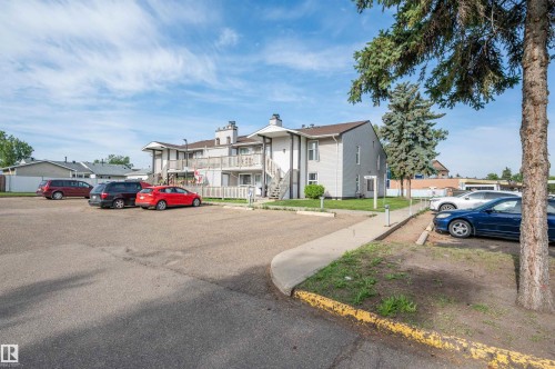 Asphalt parking area with multiple parking spaces and a pedestrian sidewalk - 15017 26 Street Nw, Edmonton, AB 