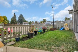 Fenced backyard featuring a manicured lawn, an elevated garden bed, and mature trees - 