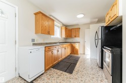 Functional kitchen featuring wood cabinetry, stone-look countertops, and included refrigerator, stove, and dishwasher - 