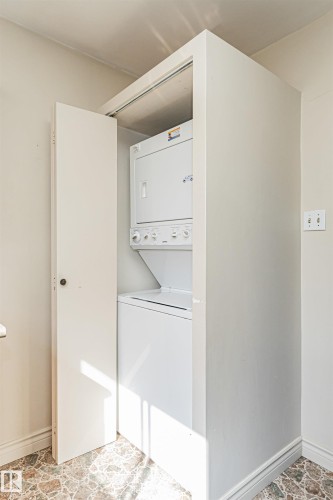 Built-in laundry closet featuring a stacked white washer and dryer, and patterned flooring - 8743 Strathearn Drive Nw, Edmonton, AB 