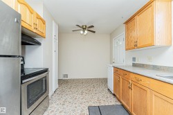 Kitchen featuring wood cabinetry, stainless steel range, stainless steel refrigerator, and a ceiling fan - 