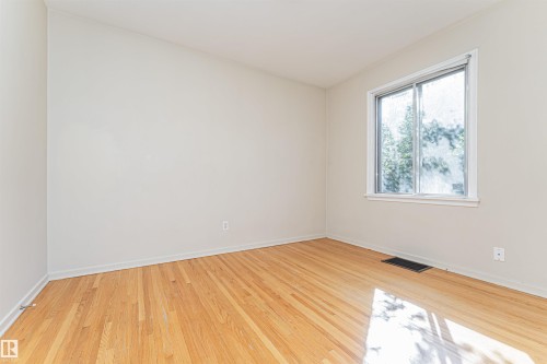 Hardwood flooring, light neutral wall tones, and a window with white trim - 8743 Strathearn Drive Nw, Edmonton, AB 