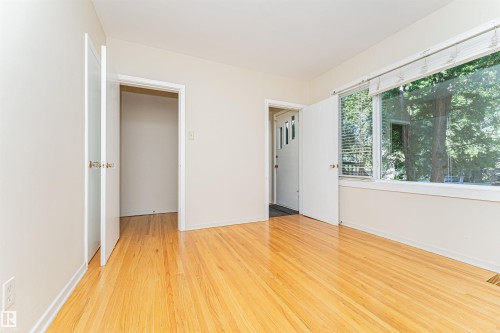 Wood-finish flooring, white walls, and a large window with natural light - 8743 Strathearn Drive Nw, Edmonton, AB 