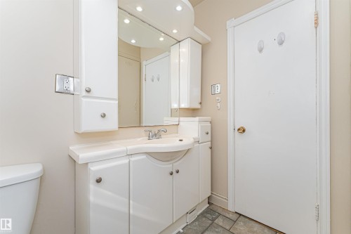 White vanity with an integrated sink, polished chrome faucet, and mirrored wall - 8743 Strathearn Drive Nw, Edmonton, AB 