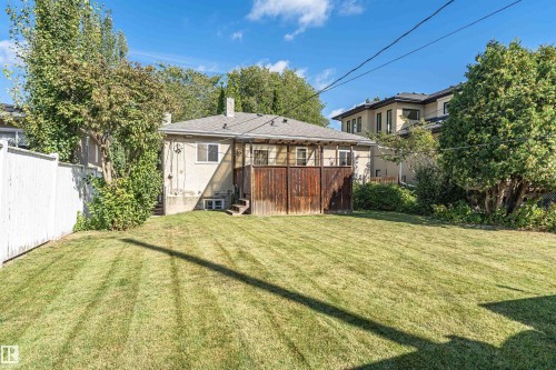 Expansive green lawn with a white fence perimeter and mature trees - 8743 Strathearn Drive Nw, Edmonton, AB 