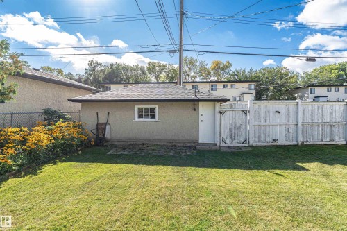 Expansive grassy yard with a detached structure featuring a window and side door - 8743 Strathearn Drive Nw, Edmonton, AB 