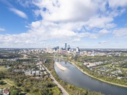 Aerial perspective of a city skyline with multiple high-rise structures, a wide river with an exposed sandbar, and extensive green spaces - 