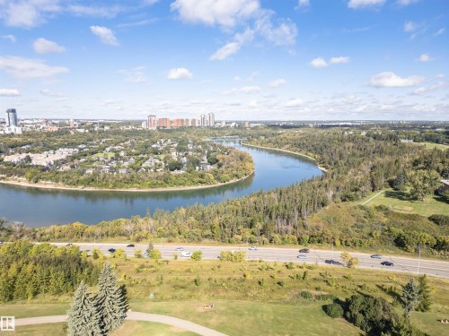 Riverfront setting with a surrounding urban landscape, mature trees, and a developed roadway - 8743 Strathearn Drive Nw, Edmonton, AB 